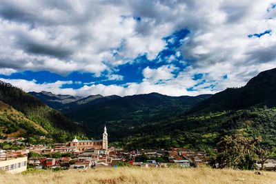 Buildings and mountains against cloudy sky in town