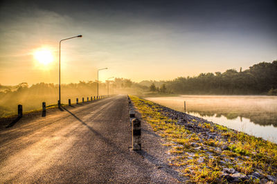 Road by street against sky during sunset