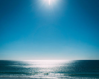 Scenic view of sea against blue sky on sunny day