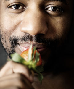 Close-up portrait of man eating strawberry