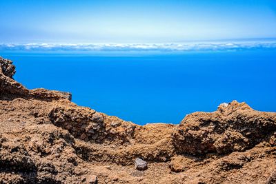 Rock formations by sea against blue sky