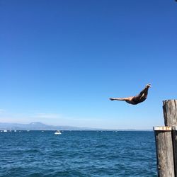 Full length of man diving in sea against blue sky