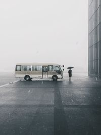 Man crossing road by van in city against sky