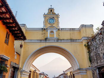 Antigua guatemala arch of santa catalina. colorful yellow el arco city scape with volcano agua.