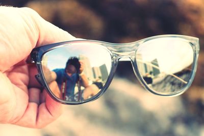 Reflection of man holding sunglasses