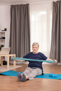 Senior woman exercising with resistance band at home