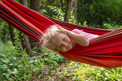 Portrait of smiling woman relaxing on hammock in forest