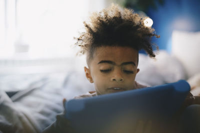 Close-up of boy using digital tablet on bed at home