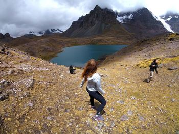 Rear view of women walking on mountain against sky