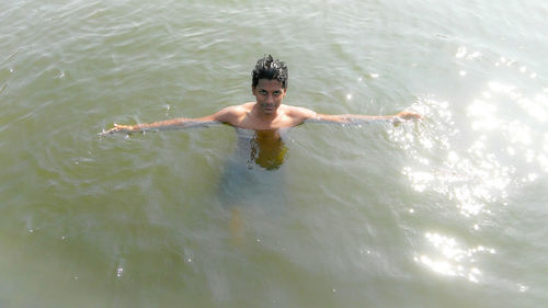 Portrait of shirtless boy swimming in water