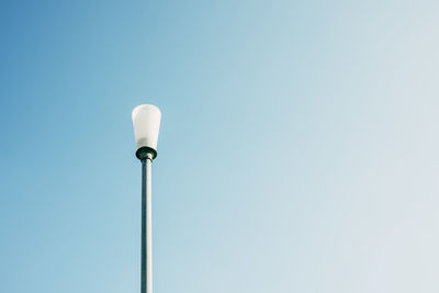 Detail view of broken street lamp without roof against blue sky