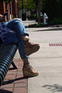 Low section of woman sitting on bench in city