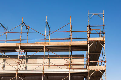 Low angle view of crane against clear blue sky