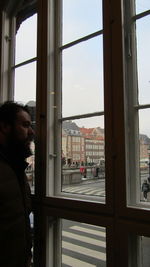 Side view of man looking through window