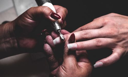 Cropped image of beautician doing manicure to customer hands