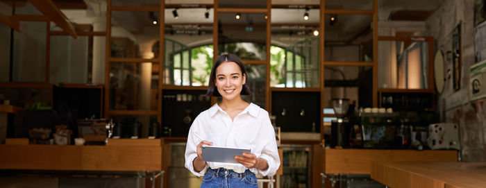 Portrait of young woman standing in library