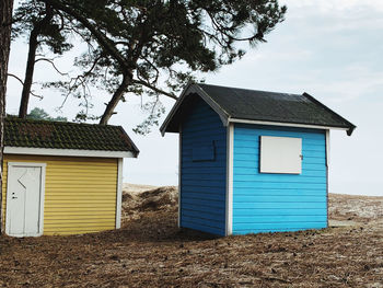 House on beach by building against sky