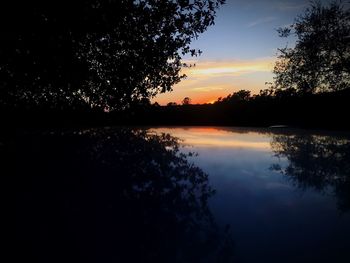 Silhouette trees by lake against sky during sunset