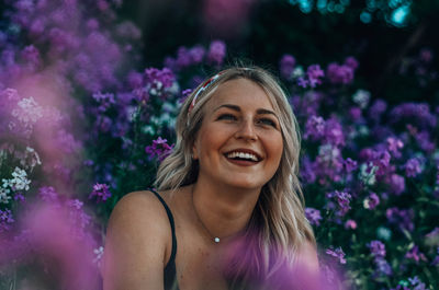 Portrait of smiling young woman against purple flowering plants