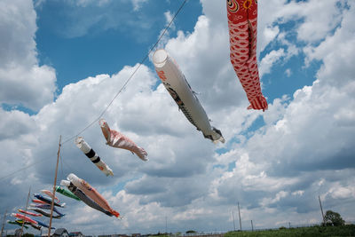 Low angle view of fish streamers hanging against sky