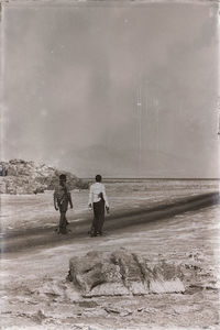 Rear view of people standing on land against sky