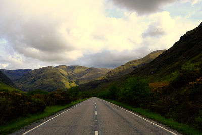 Country road along landscape against sky