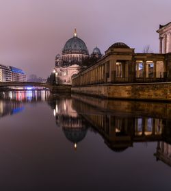 Reflection of illuminated buildings in water at sunset