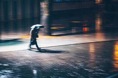 Full length of man walking on wet street in city