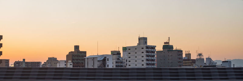 Buildings in city against clear sky during sunset