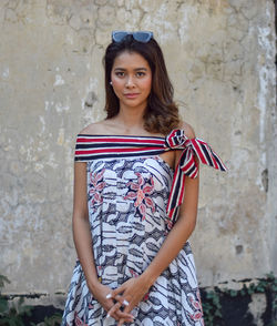 Portrait of a beautiful young woman standing against wall