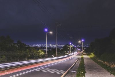 Light trails on road against sky at night