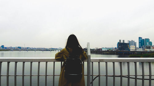 Rear view of woman looking at cityscape against sky