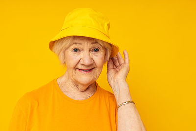 Portrait of young woman against yellow background