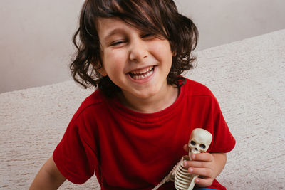 Portrait of smiling boy with toy against wall