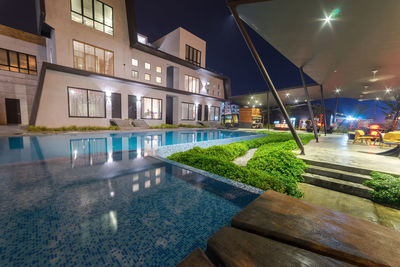 Buildings by swimming pool at night
