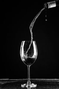 Close-up of wineglass on table against black background