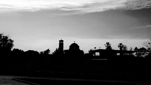 Silhouette trees with buildings in background