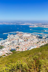 High angle view of townscape by sea against blue sky