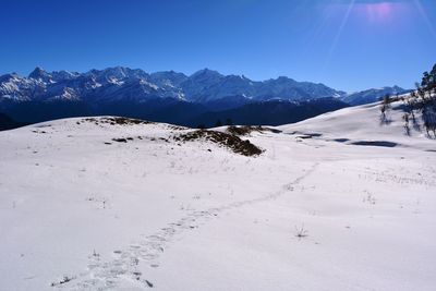 Scenic view of snow covered mountains against blue sky