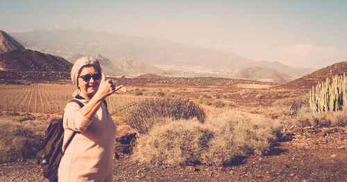 Woman gesturing shaka sign on land