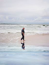 Man walking at beach against sky