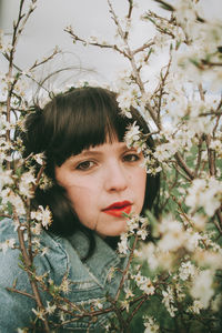 Portrait of beautiful young woman against plants