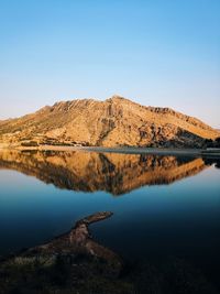 Scenic view of lake by mountains against clear blue sky