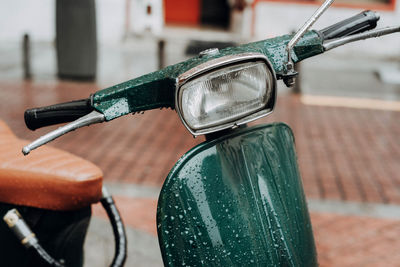 Detail of a classic green vespa scooter parked in the sidewalk.