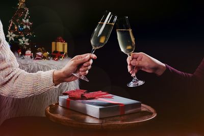 Midsection of couple toasting champions flutes during christmas 