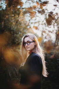 Young woman wearing hat standing against plants