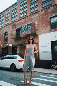 Full length of beautiful woman standing on road against building