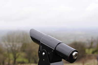 Close-up of machine part on landscape against sky