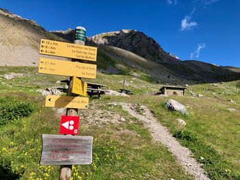 Road sign on field against sky