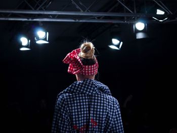 Woman standing against illuminated lights at night